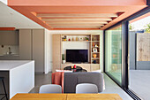 Modernes Wohnkonzept mit offenem Küchen-Essbereich und korallenroter Decke