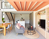 Modern living room with open-plan kitchen and coral-colored ceiling beams