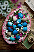 Easter eggs in blue and natural colours with flowers on a pink vintage plate