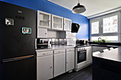 Küchenzeile in Schwarz-Weiß mit blauer Wand und Hängeleuchte