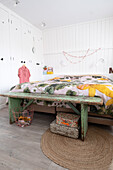 Bedroom with floral bed linen and rustic wooden bench in front of the bed