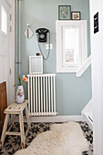 Retro hallway with wall-mounted telephone, wooden stool and tiled floor with star pattern