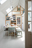 Dining room with wooden bench, chairs, sloping ceilings and windows