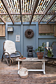 Covered terrace with rattan armchairs, wood-burning stove and rustic table