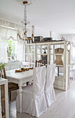 Dining room in shabby chic style with white wooden table and chair covers