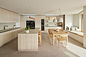 Open-plan kitchen area with wooden furniture and seating area by the window