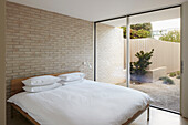 Schlafzimmer mit Doppelbett, weißer Bettwäsche und Blick auf den Innenhof