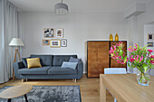 Brightly furnished living room with blue sofa and flower arrangement on the table