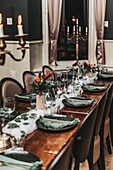 Eleganter Esstisch mit Kerzenleuchter, dunklen Tellern und grünen Servietten