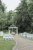 Freiluft-Zeremoniebereich mit weißem Pavillon und Stühlen im Garten