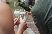 Sparkling wine is poured into glasses outdoors