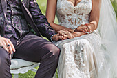 Brautpaar in Festkleidung hält Hände während Trauung