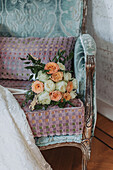 Strauß mit Rosen und Eukalyptus auf antikem Stuhl mit Samtbezug