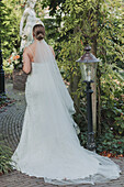 Braut mit Hochzeitskleid und Blumenstrauß im Park