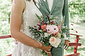 Brautpaar hält Hochzeitsstrauß mit Rosen und Eukalyptus
