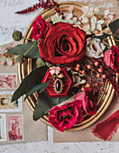 Arrangement aus Rosen, Beeren und Schmuck auf goldenem Tablett