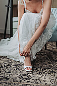 Woman in white lace dress puts on shoes