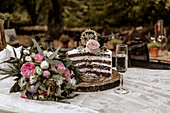 Angeschnittene Hochzeitstorte mit Dekoration, Brautstrauß und Sektglas