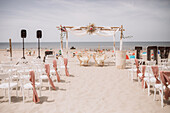 Boho-style wedding ceremony on the beach, decoration in white with pink accents