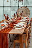 Gedeckter Esstisch mit Herbstdekoration, Trockenblumen und Kerzen