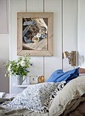 Wood-panelled bedroom with bouquet of flowers and picture