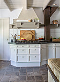 Country kitchen with white cabinets, stone floor and wooden beams