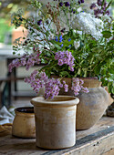 Rustic clay jugs with summer flower bouquet on wooden table