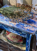 Trockenblumenstrauß auf blau bemaltem Vintage-Holzhocker