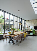 Dining room with large wooden table and upholstered chairs in front of large windows