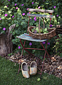 Decorative garden chair with wicker basket, silverware and clogs