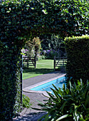 Lush garden with pool and ivy-covered archway