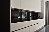 Moderne Küchenzeile mit weißen Fronten und schwarzer Arbeitsplatte