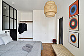 Modernes Schlafzimmer mit Kunstwerken und Rattan-Pendelleuchte
