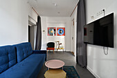 Modernes Wohnzimmer mit blauem Sofa, TV-Bildschirm und Couchtisch