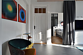 Wohnzimmer im Altbau mit Designersessel, Kunstwerken und Blick ins Schlafzimmer