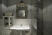 Baroque mirror above washbasin in bathroom with shower cubicle