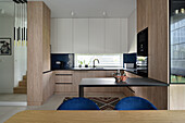 Moderne Küche mit Holzelementen und blauen Esszimmerstühlen
