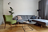 Wohnzimmergestaltung mit grauem Ecksofa und grünem Sessel