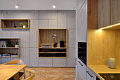 Moderne Wohnzimmergestaltung mit hellgrauem Einbauregal und Küchenzeile