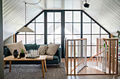 Living area in the attic with large windows and spiral staircase