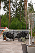 Seating area on wooden terrace with black wicker chairs and large sofa