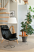 Reading chair with floor lamp and houseplant on round carpet in front of spiral staircase