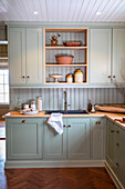 Country-style kitchen with pastel green cabinets and wooden worktop