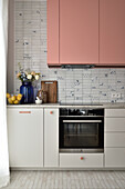 Modern kitchen with pink cupboards and blue and white tiled splashback