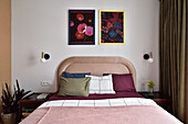 Schlafzimmer mit gepolstertem Kopfteil und floralen Kunstwerken an der Wand