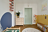 Children's room with pastel-coloured wall design and wooden furniture