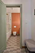 Bathroom with pastel green door, terracotta-coloured wall and tiled floor