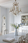 Dining room with chandelier, grandfather clock and flower vase on dining table