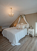 Romantic bedroom with chandelier, canopy and white bed linen