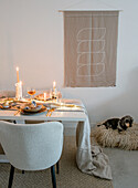 Set dining table with candles and dog in dog bed